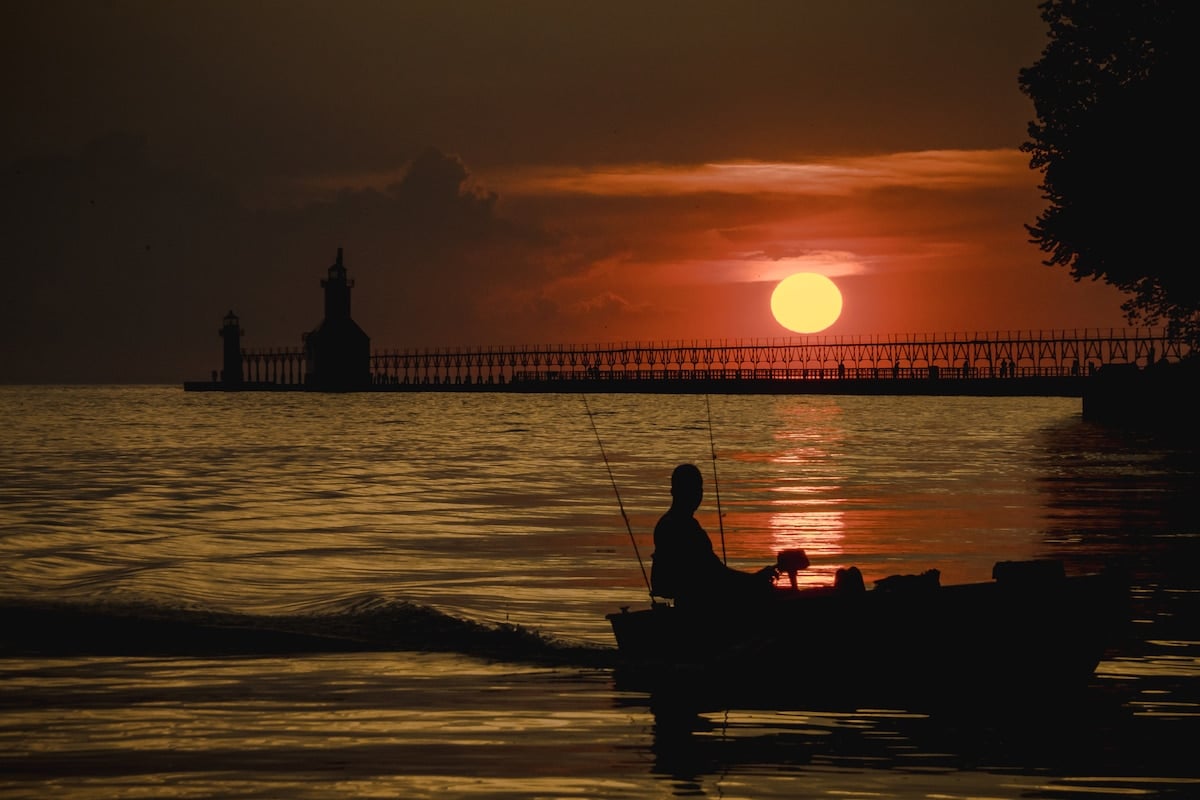 A man on a fishing boat as the sun goes down