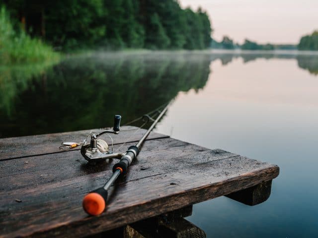 Spinning Reel and rod sitting on a pier overlooking a lake