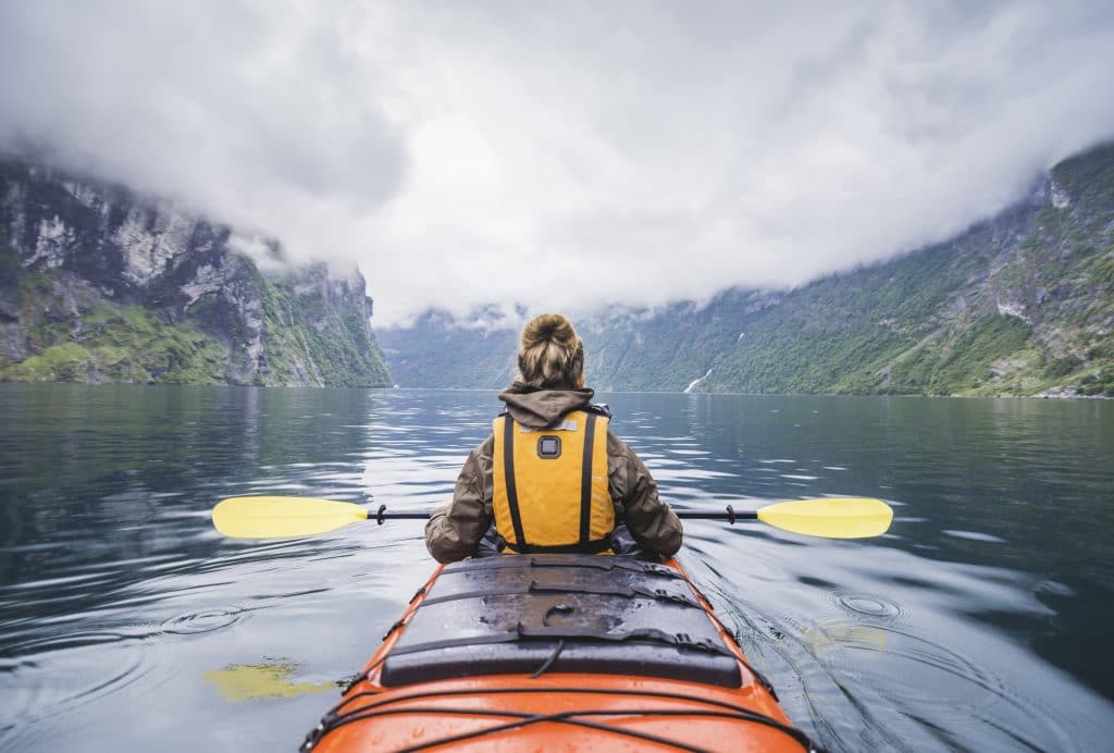 Woman kayaking in Geiranger fjord in Norway.