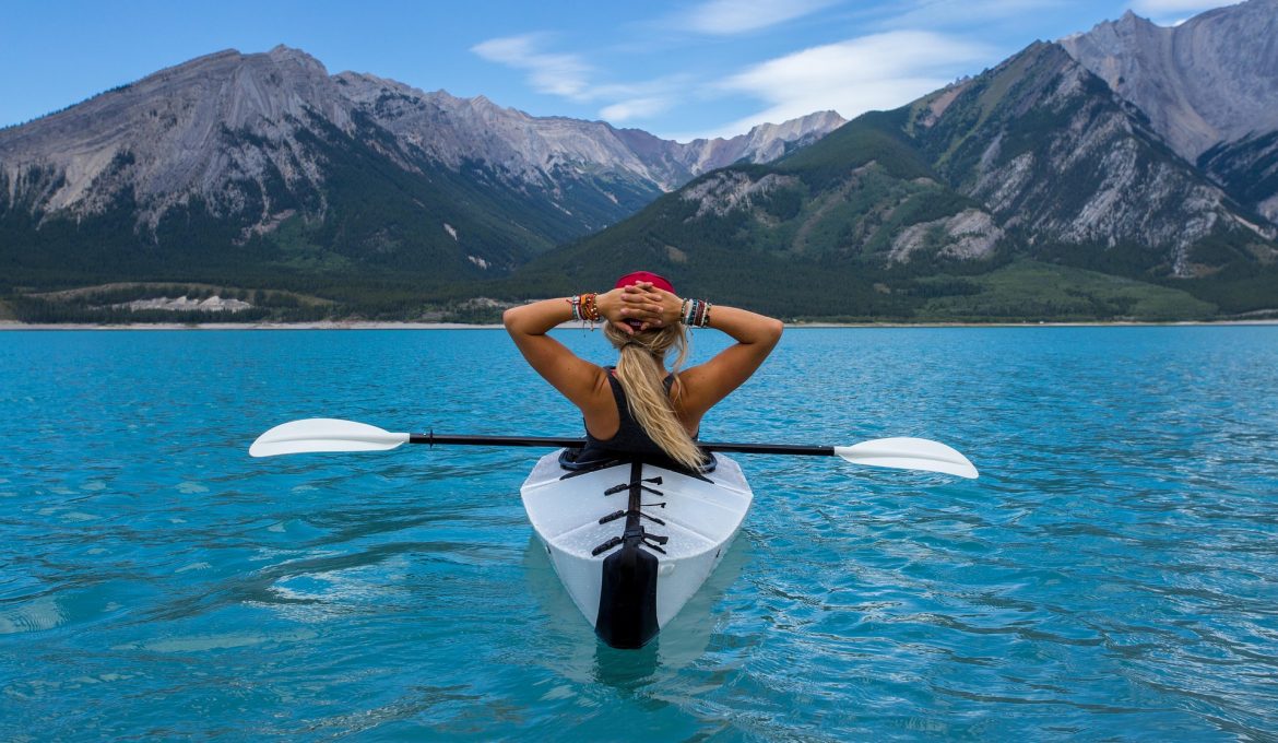 woman relaxing on a kayak with mountains in the background