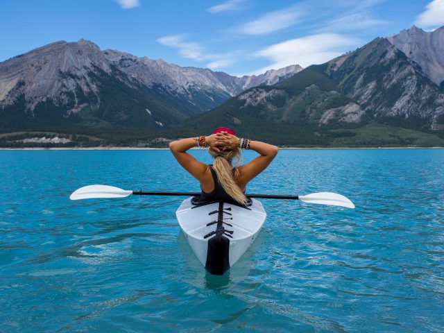 woman relaxing on a kayak with mountains in the background