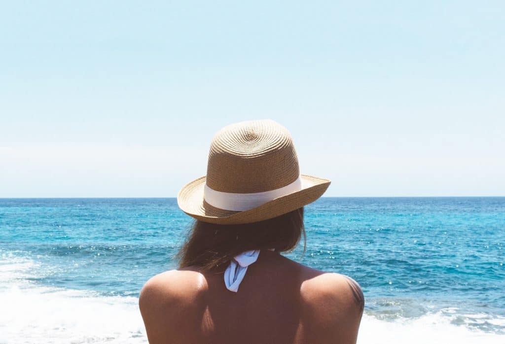 Woman in swimsuit at beach wearing a hat