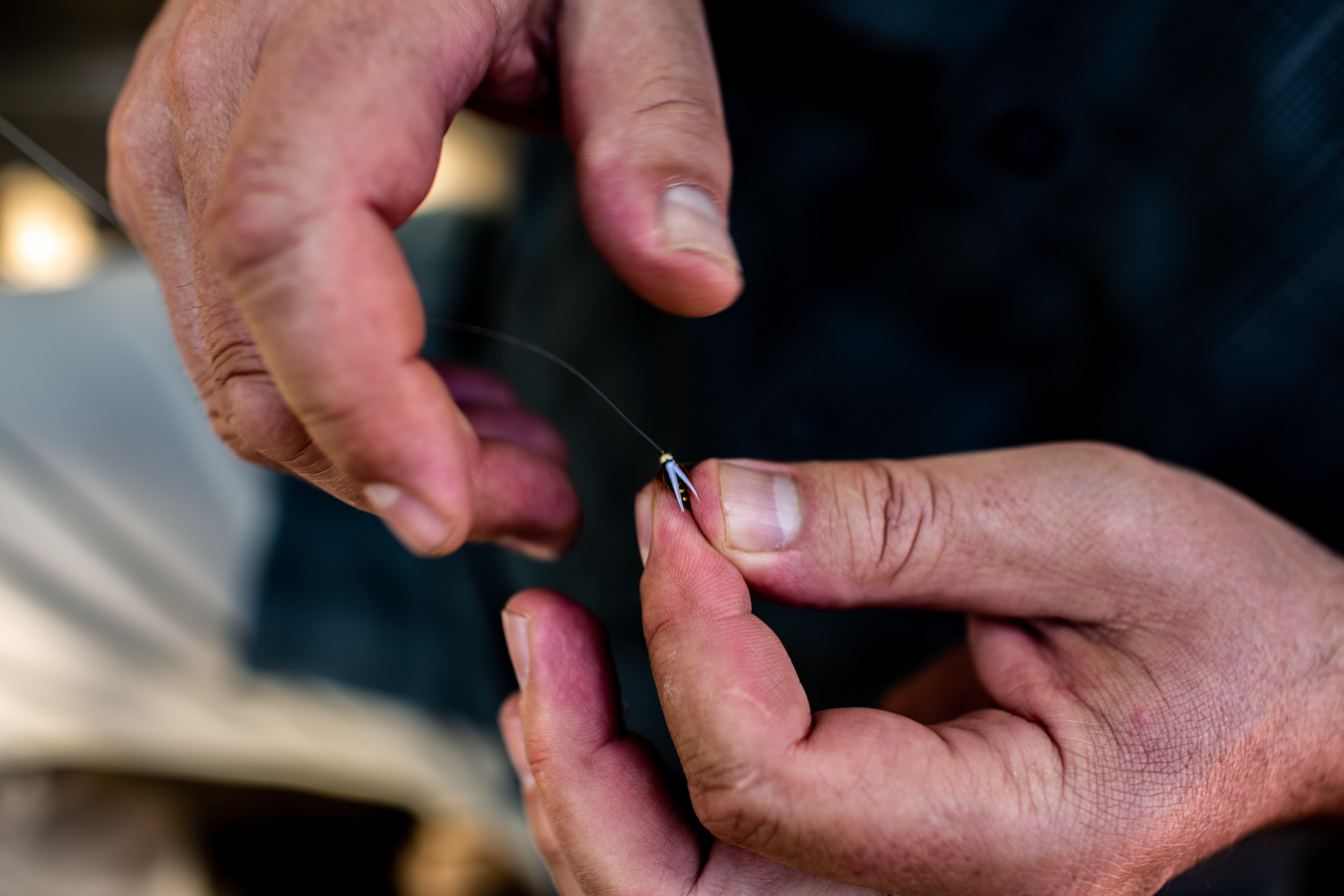 Man tying a fly onto a tippet