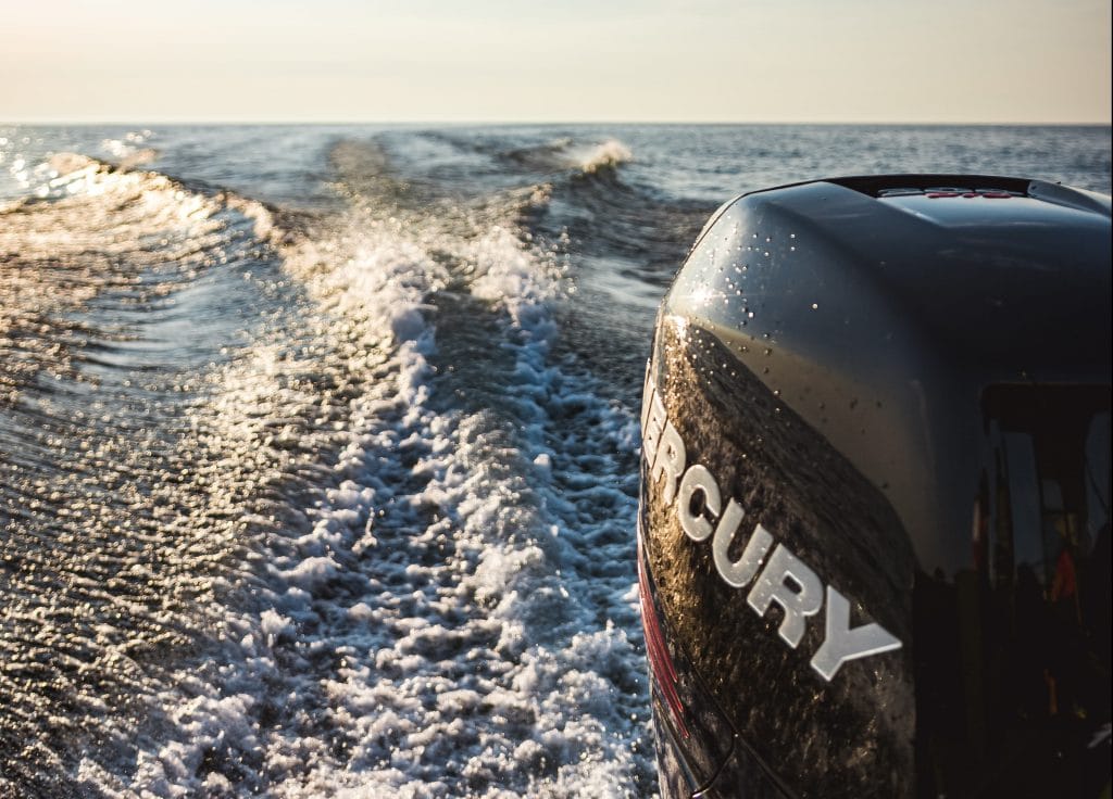 Black mercury outboard motor making wake on lake