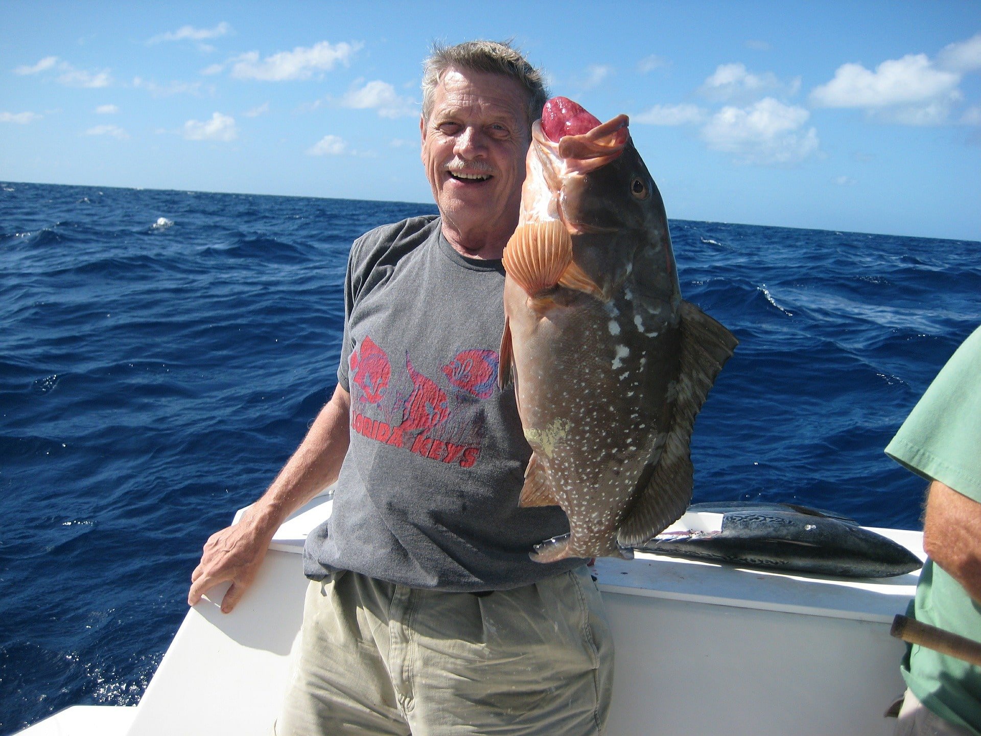 man catching grouper while deep sea fishing during a winter fishing trip
